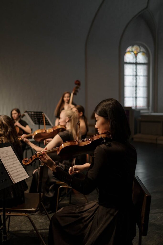 A group of musicians in a church performing orchestral music with violins and cellos.